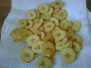 Rodajas de plátano frito escurriendo en papel absorbente.